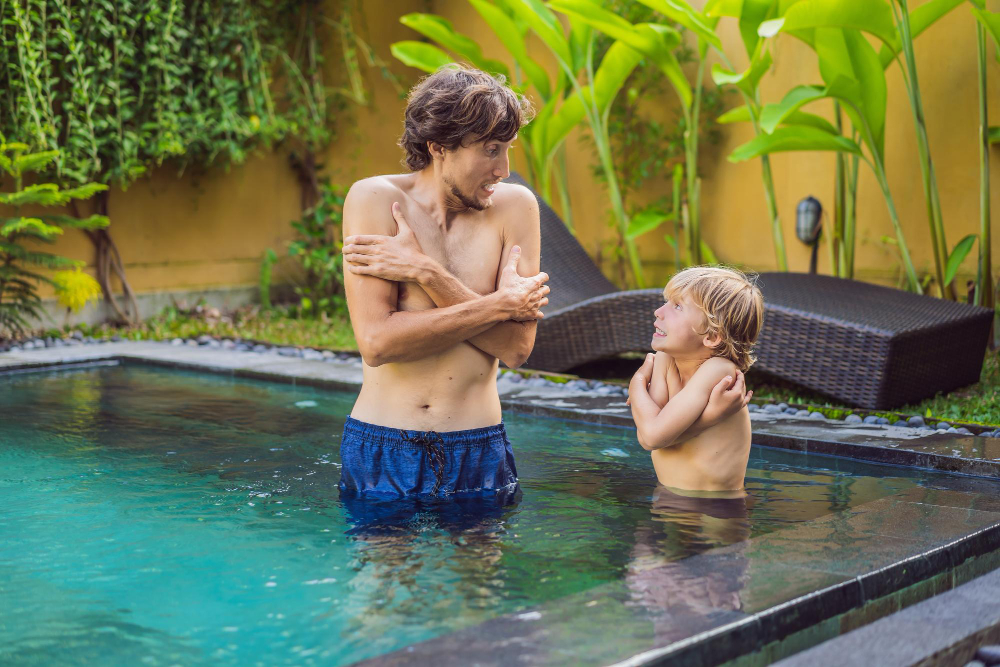 Pai e filho com frio na piscina gelada sem os benefícios do aquecedor solar